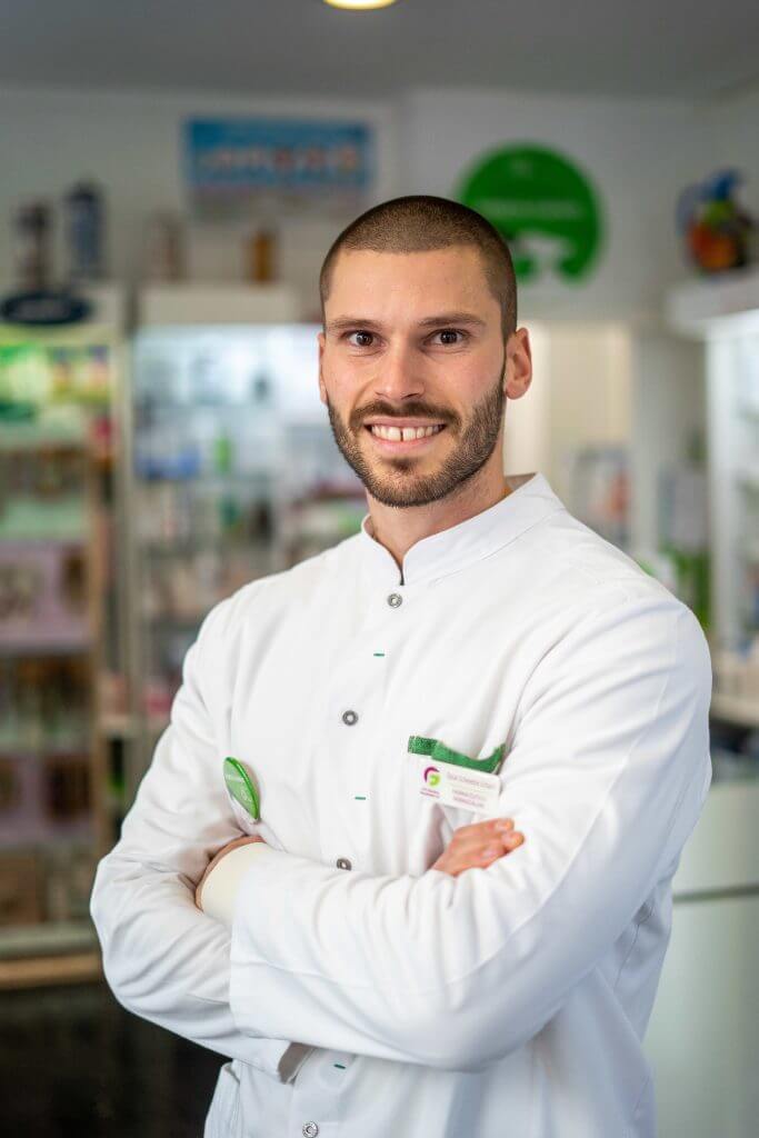 Farmacéutico titular de la farmacia mirando hacia la cámara.